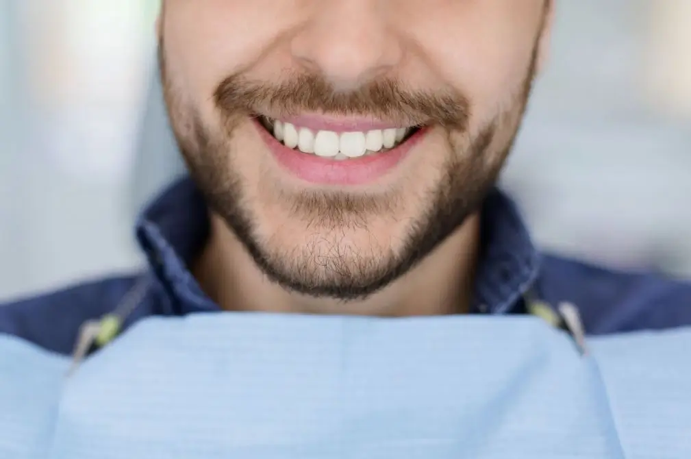 Close-up of a man’s smile in a dental exam chair.