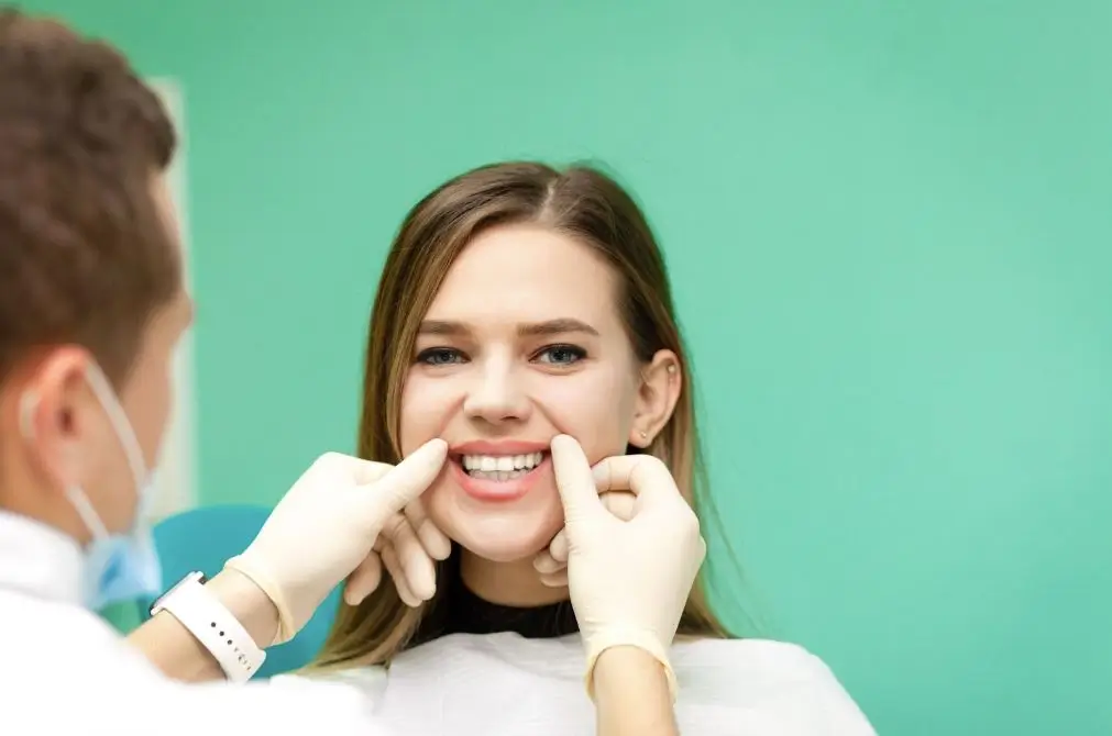 Dentist wearing gloves and examining a woman’s teeth.