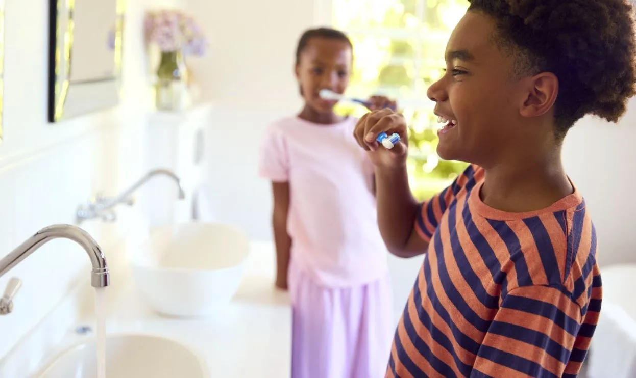 Young boy and girl at the sink brushing their teeth.