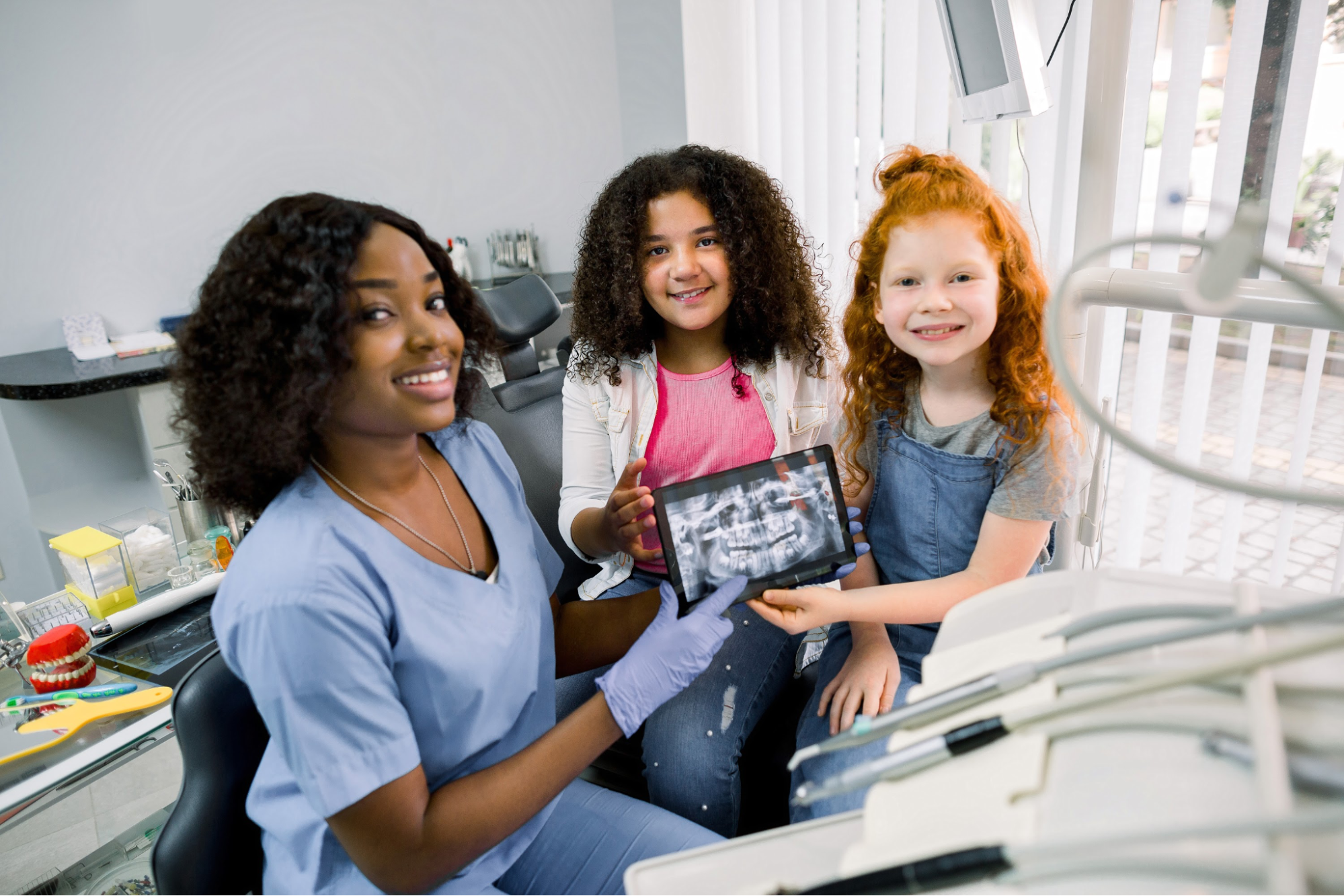 A nurse and two kids looking at a mouth X-ray